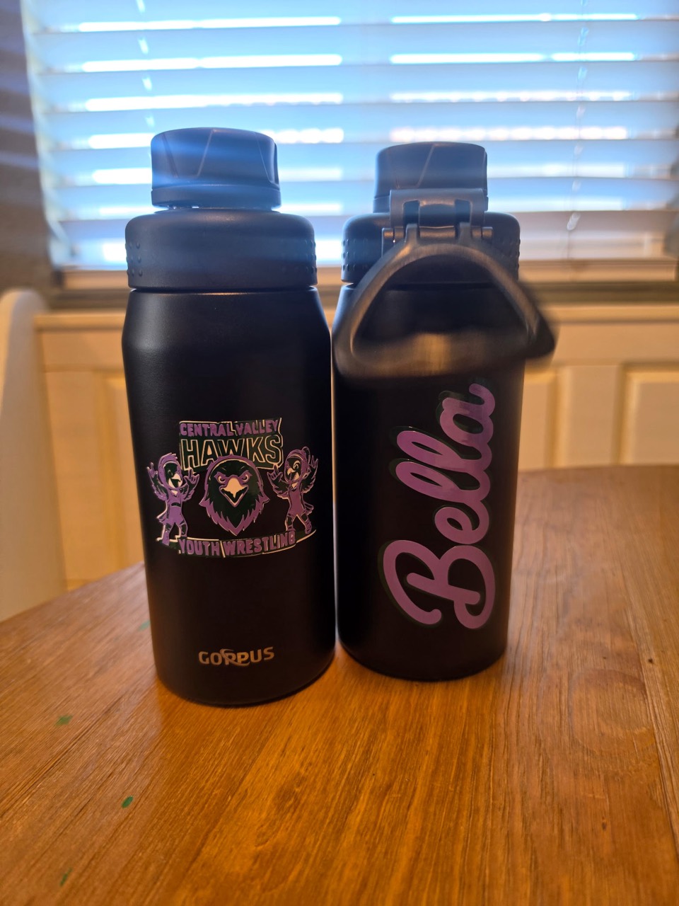 Two black water bottles customized with a wrestling logo